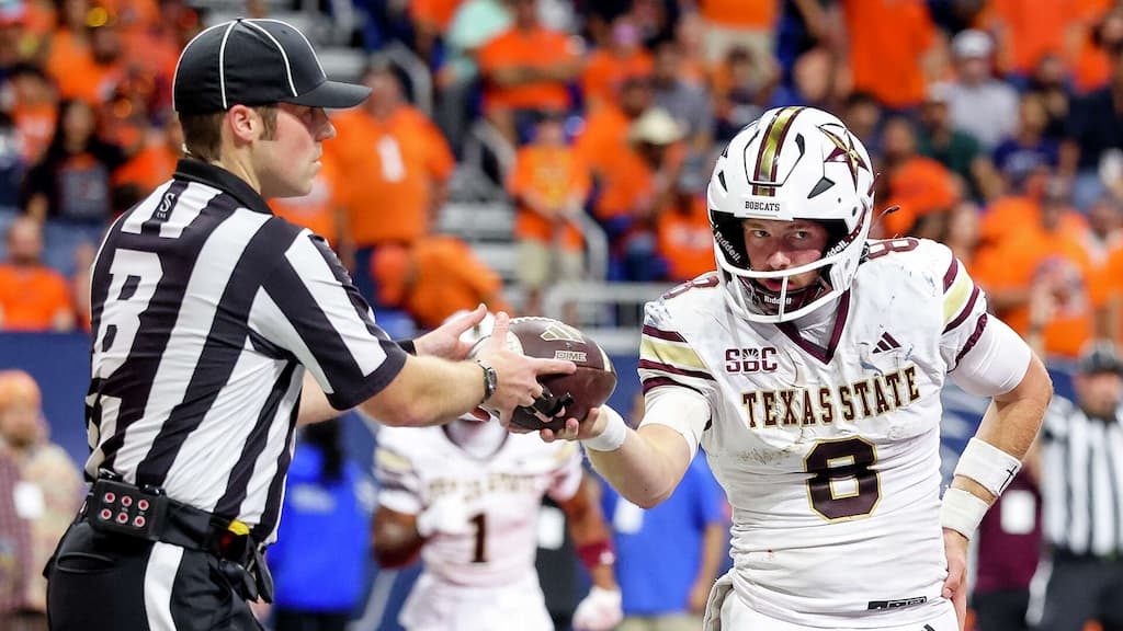 Texas State quarterback Brad Jackson hands the football to a referee during a game